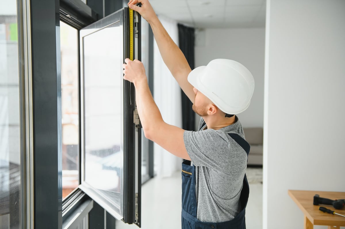 Technician installing a bay window in a new house construction site
