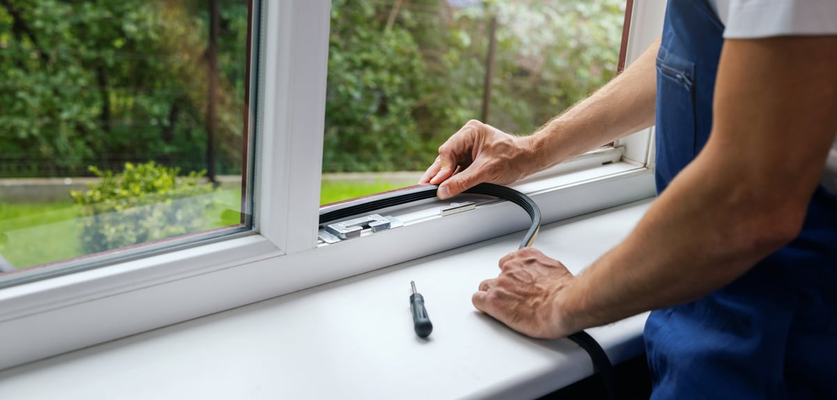 Worker installing and sealing a new residential door frame