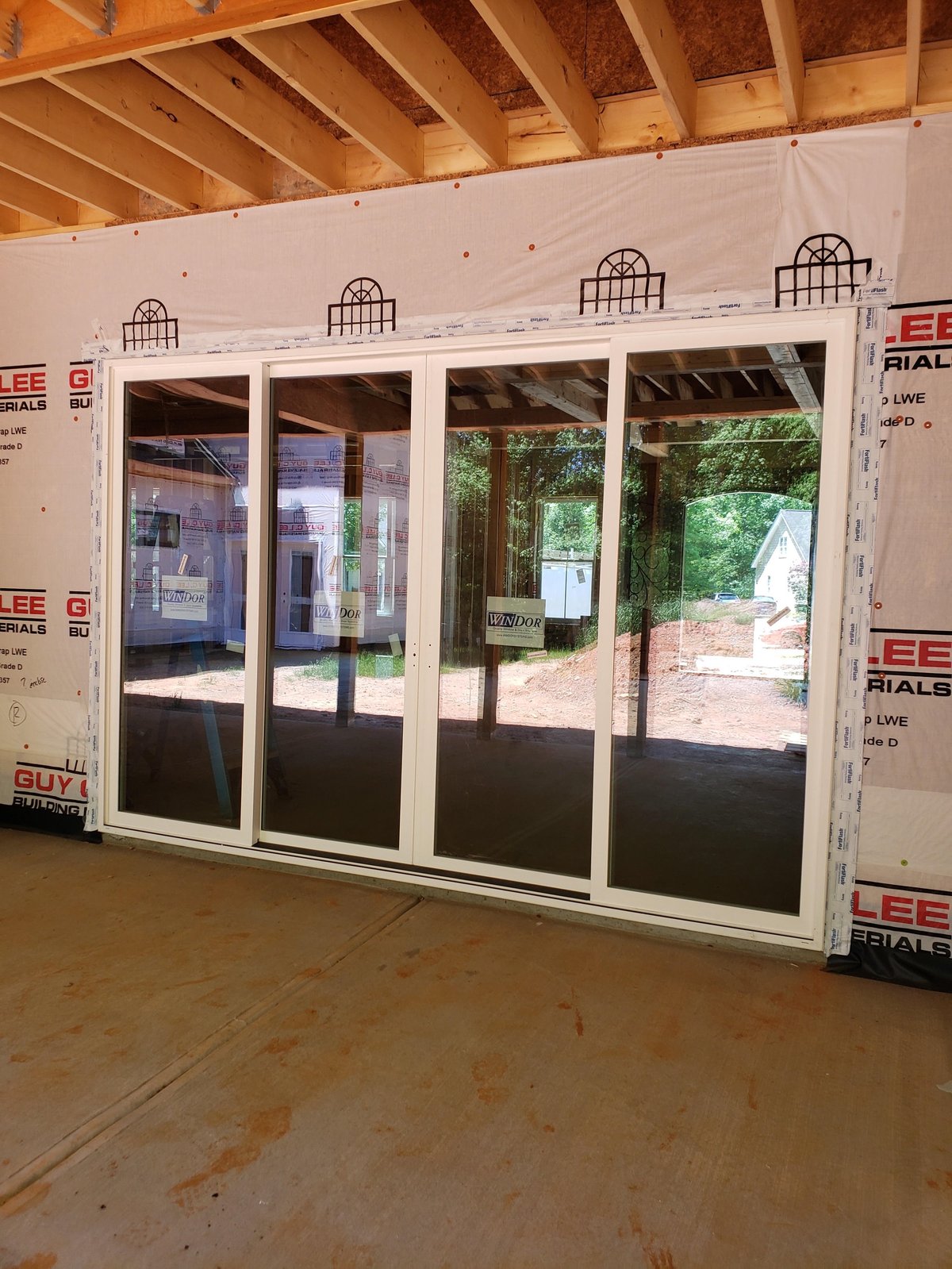 Large four-panel glass sliding doors installed in unfinished interior