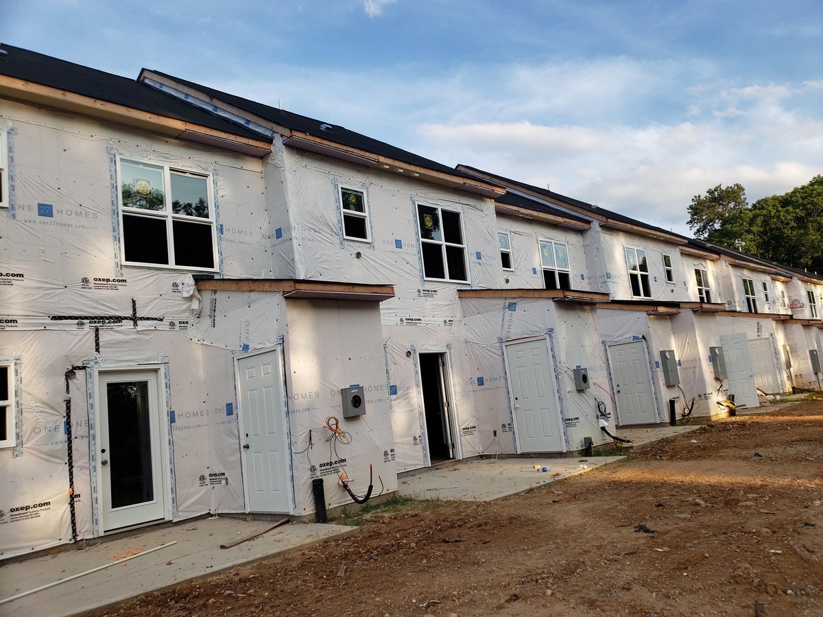 Row of new townhouses under construction with installed windows and doors